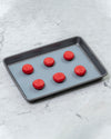 The Half Sheet Slate Baking Mat with Red Macaroons on it. 