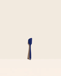 The Navy Mini Spatula on a cream background. 